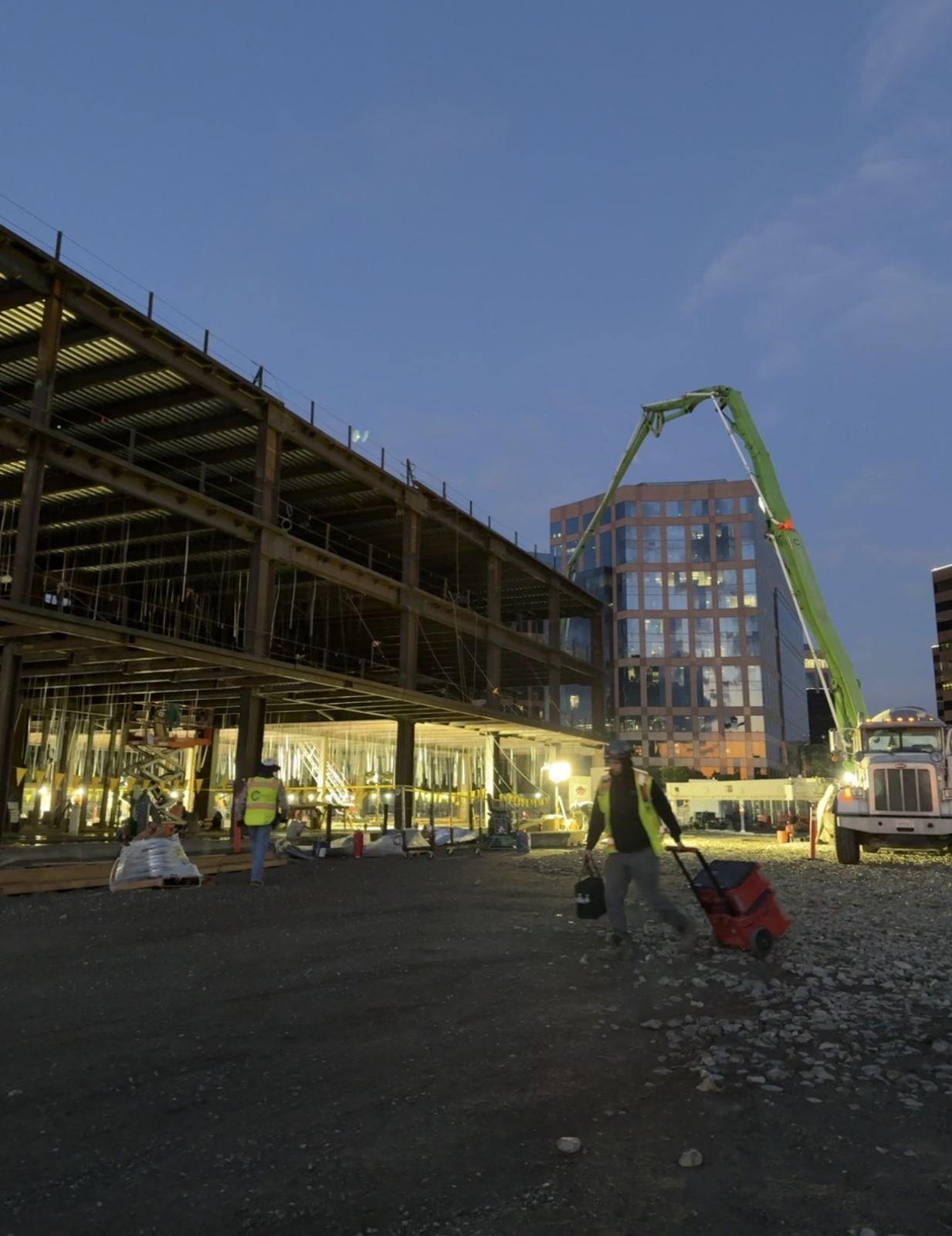 Early-morning concrete placement with a pump truck at a steel-frame building