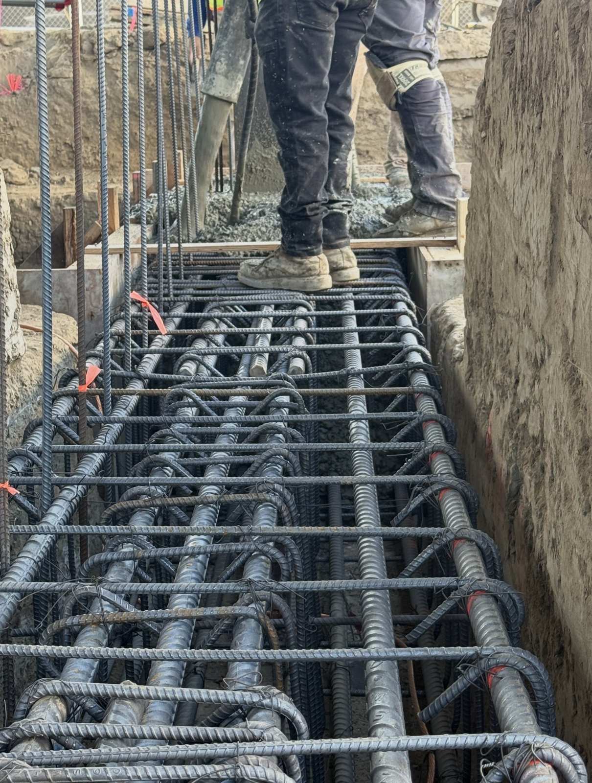 Rebar cage in a reinforced concrete footing being inspected during the concrete pour