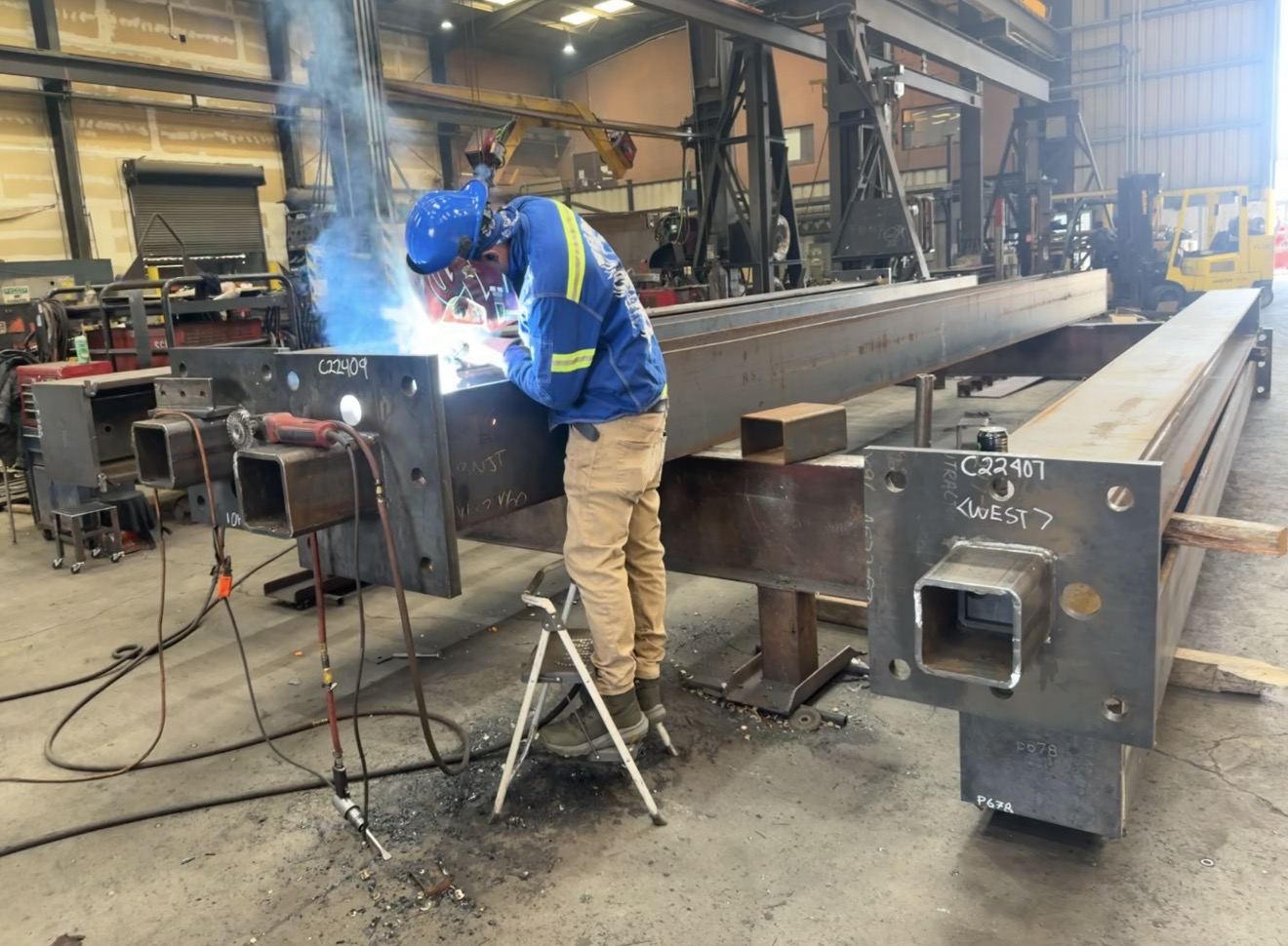 Welder working on a structural steel column in a fabrication shop